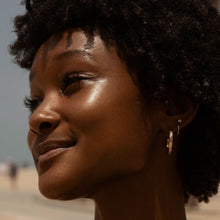 Closeup shot of girl with dewy cheeks wearing SuperDew Shimmer-Free Highlighter Balm by Tower28 Beauty